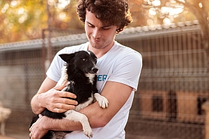 Volunteer man holding small black and white dog