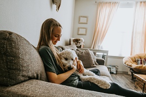 house pet sitter holding a dog while sitting on the couch