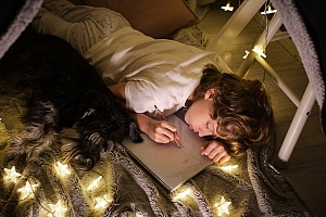 dog and boy in blanket fort surrounded by twinkle lights