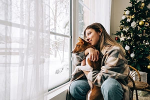 Dog inside with woman owner looking outside window at snow in Northern Virginia