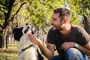 a man petting his shelter dog that he adopted two years ago and is now taking her on walks in the park