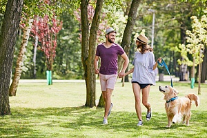 couple walking dog in secluded park to distract the dog barking at another dog