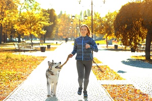 Happy,Young,Woman,Jogging,With,Her,Dog,In,Park