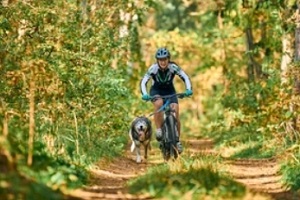man cycling with a dog on a dog walking trail 