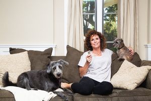 A female house pet sitter watching tv with two pet dogs