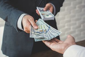 A man giving dollar notes to the other person