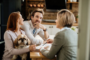 A female pet sitter making a care list of the pet with the help of his owners