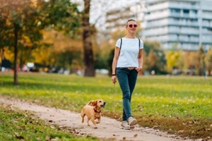 woman walking in the park with a dog in autumn