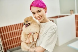 smiling female pet sitter with purple hair holding pomeranian spitz in Northern VA