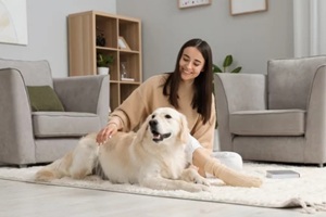 happy woman with cute labrador retriever dog on floor at home